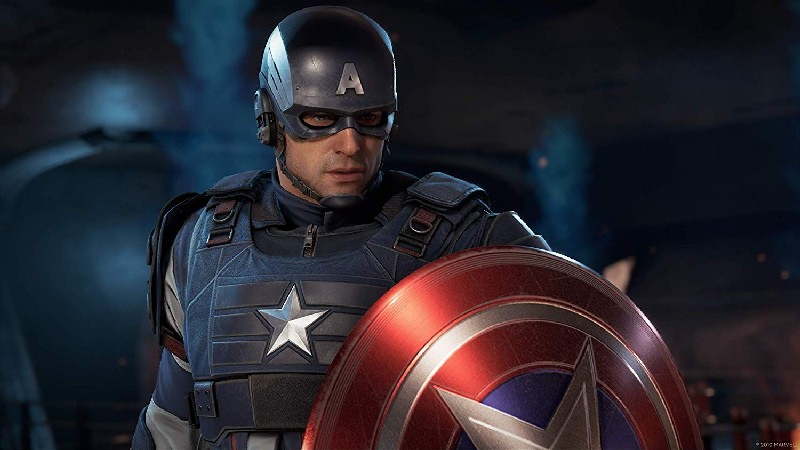 Capitán América con casco y uniforme, sosteniendo su escudo. Está mirando hacia un lado.