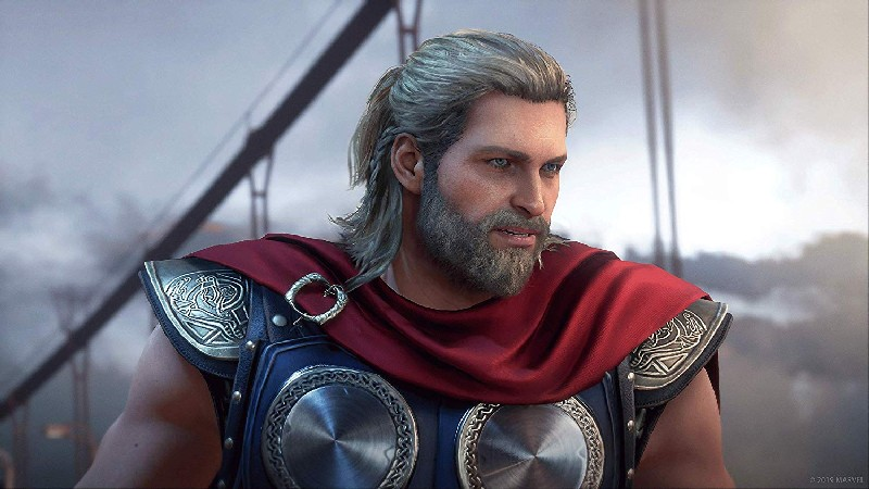 Thor, con pelo largo rubio, barba y armadura, mira al lado, severamente.
