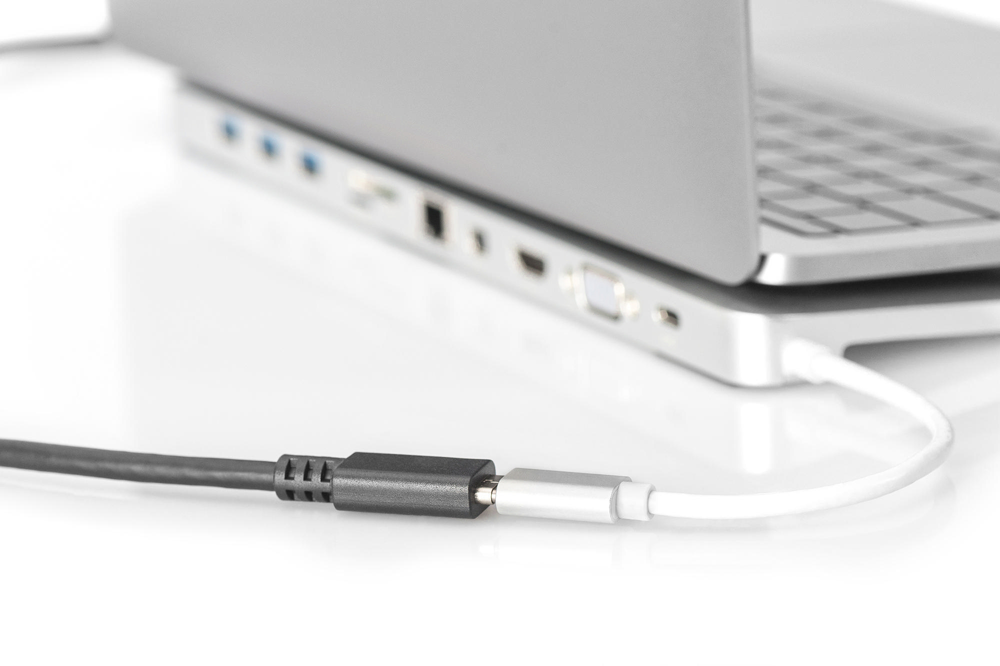 Graues Kabel wird in einen silbernen Adapter an einem Laptop angeschlossen.