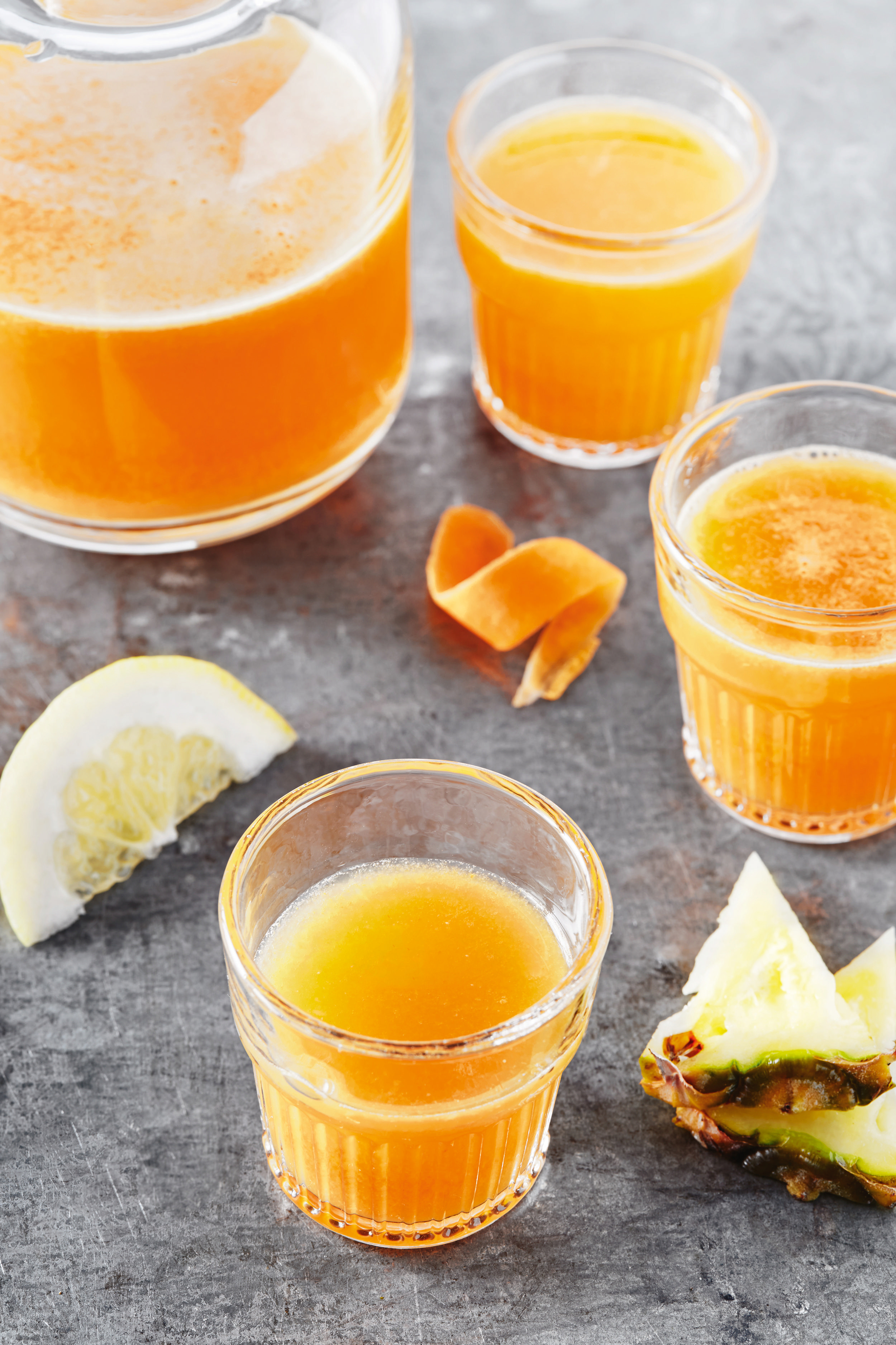 Orangensaft in Gläsern mit Zitronenspalte und Ananas.