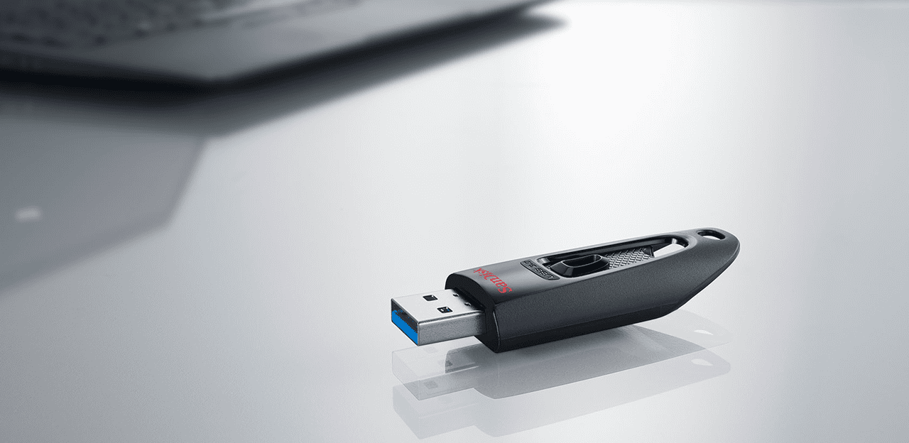 Schwarz-grauer USB-Stick mit USB-Anschluss auf reflektierender Oberfläche.