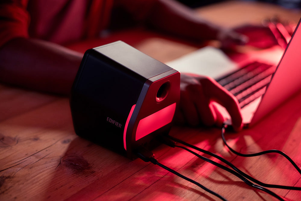 Schwarzer Lautsprecher mit rotem Licht, in der Nähe des Laptops.