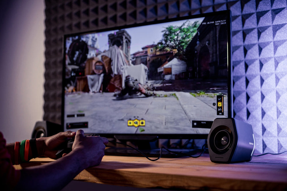 Eine Person spielt ein Videospiel auf einem großen Monitor mit Lautsprechern an den Seiten.