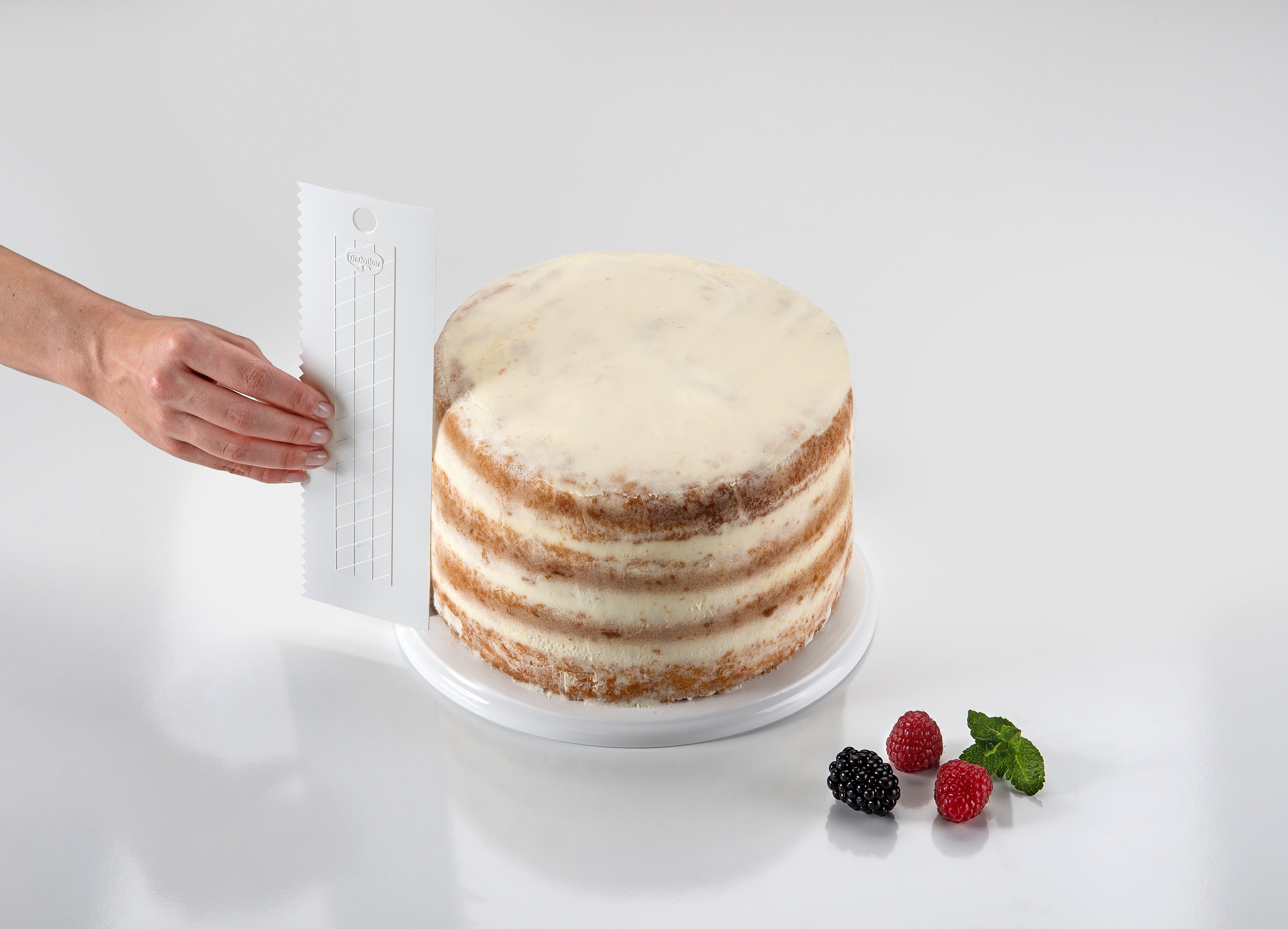 Person verziert einen runden Kuchen mit einem weißen Spatel.