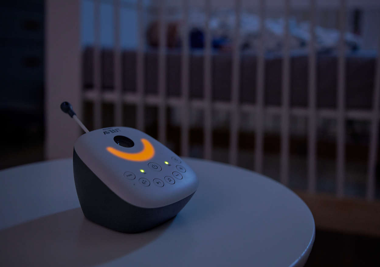 Babyphone sur une table. Lit bébé en arrière-plan. Lueur jaune.