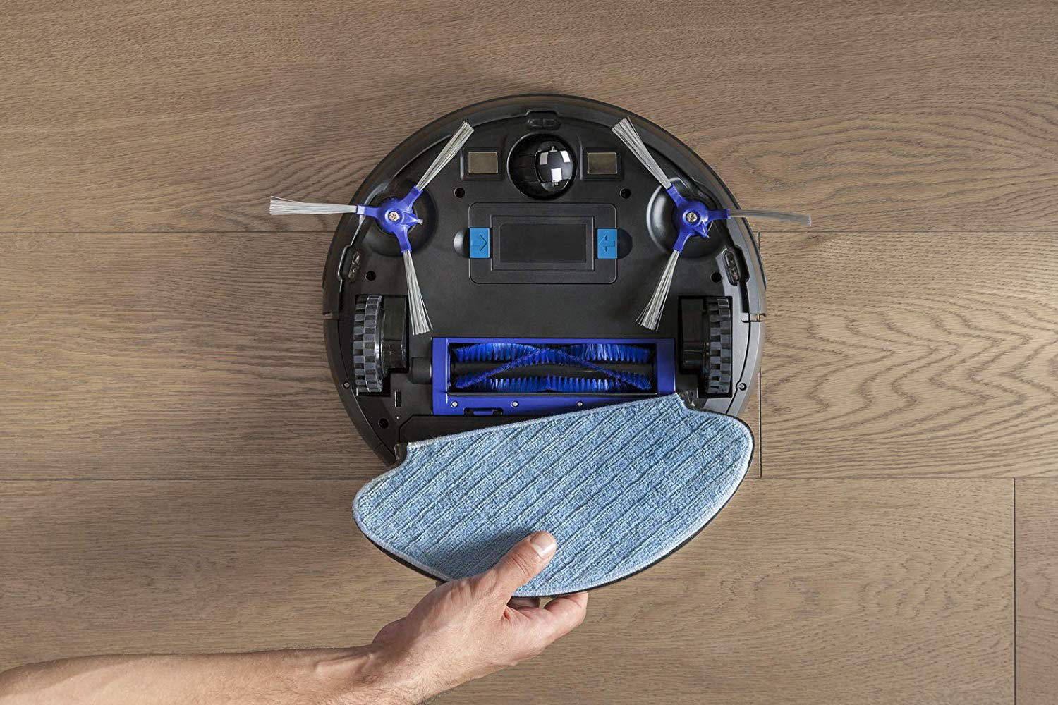Draufsicht auf einen Roboterstaubsauger mit einer Hand, die ein Pad hält.