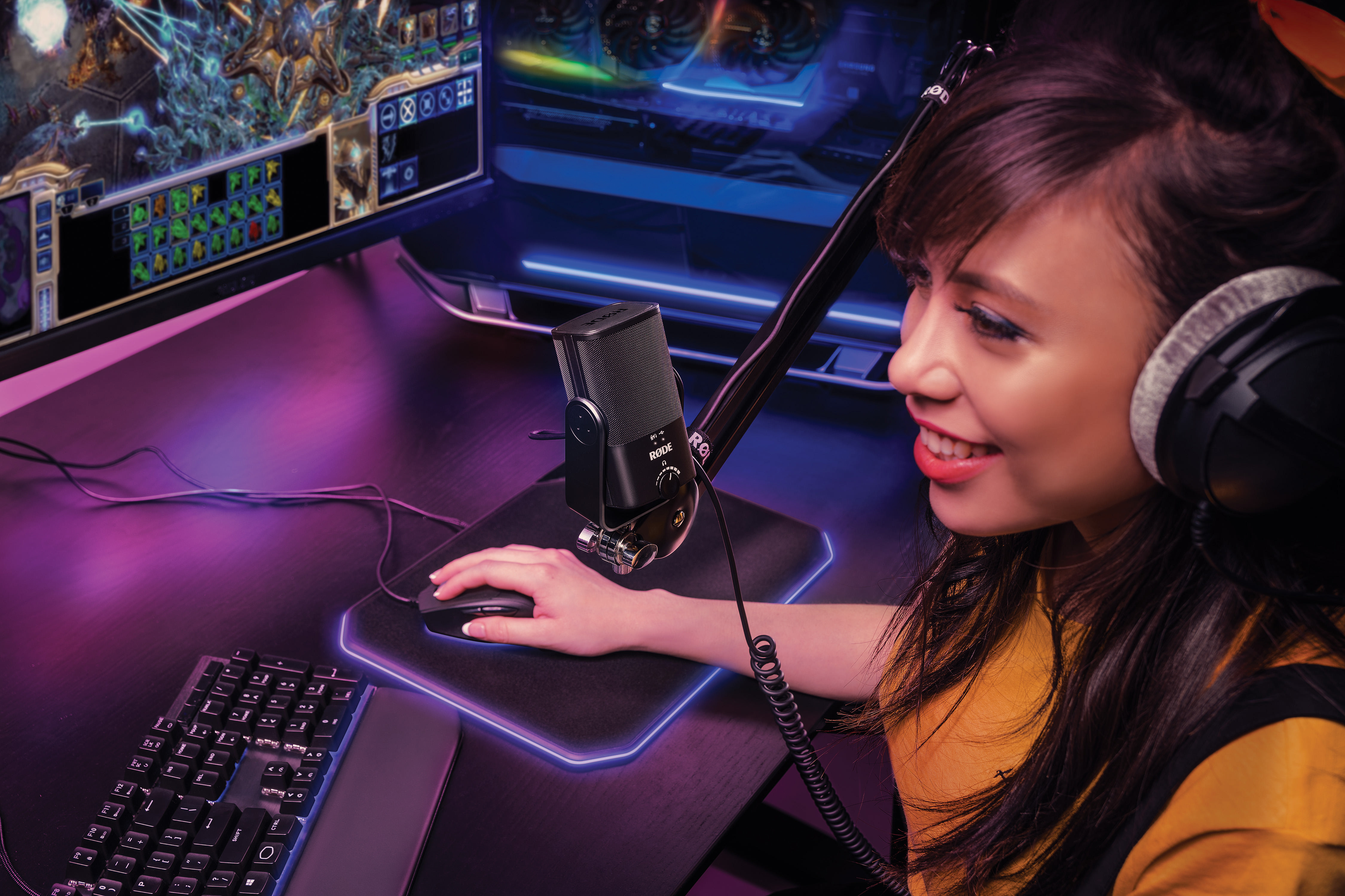 Gamerin, mit Mikrofon auf Ständer, Maus, Tastatur und Bildschirm.