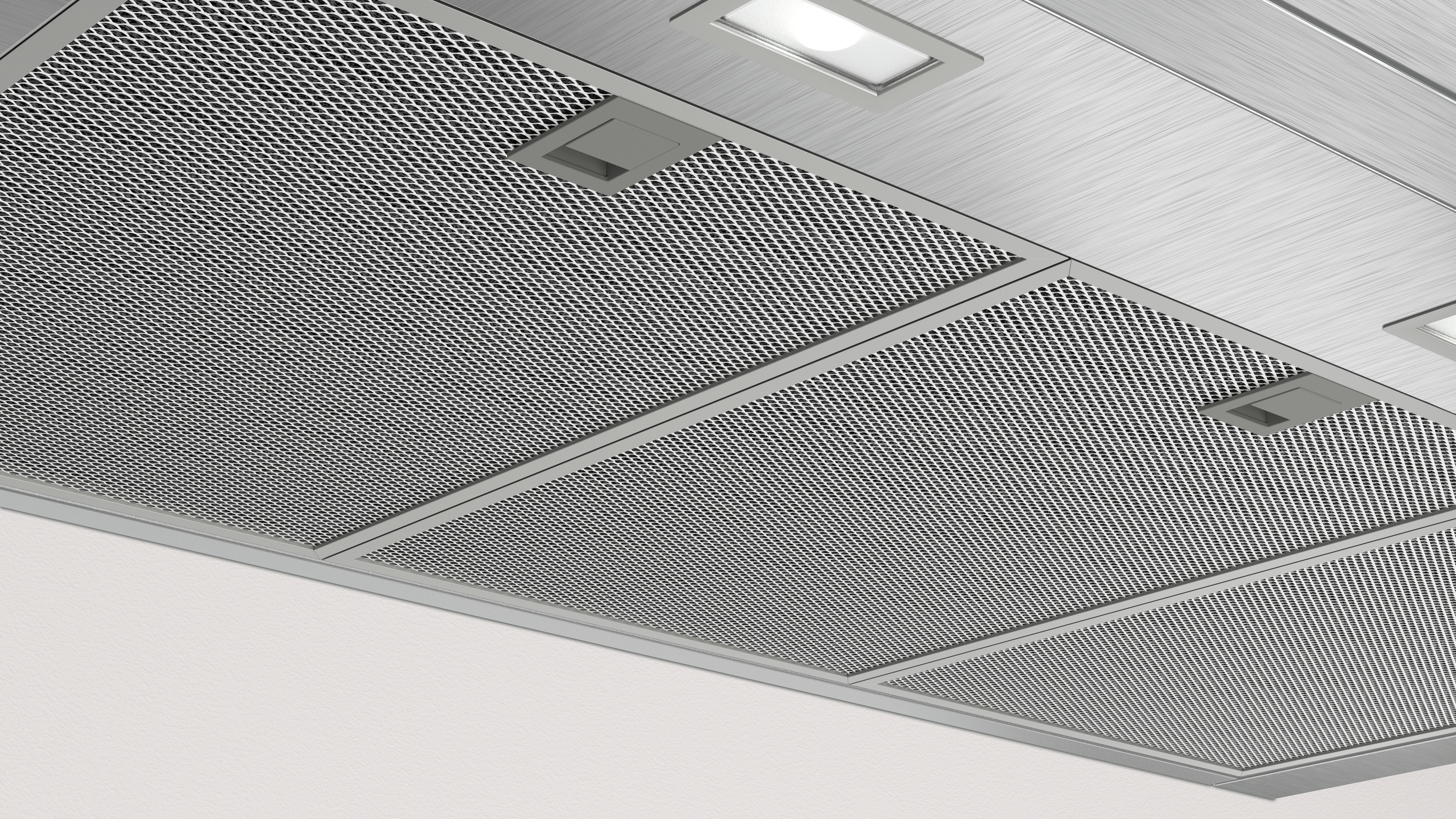 Primer plano de los filtros de la campana extractora. Malla metálica con pequeños agujeros. Forma rectangular.