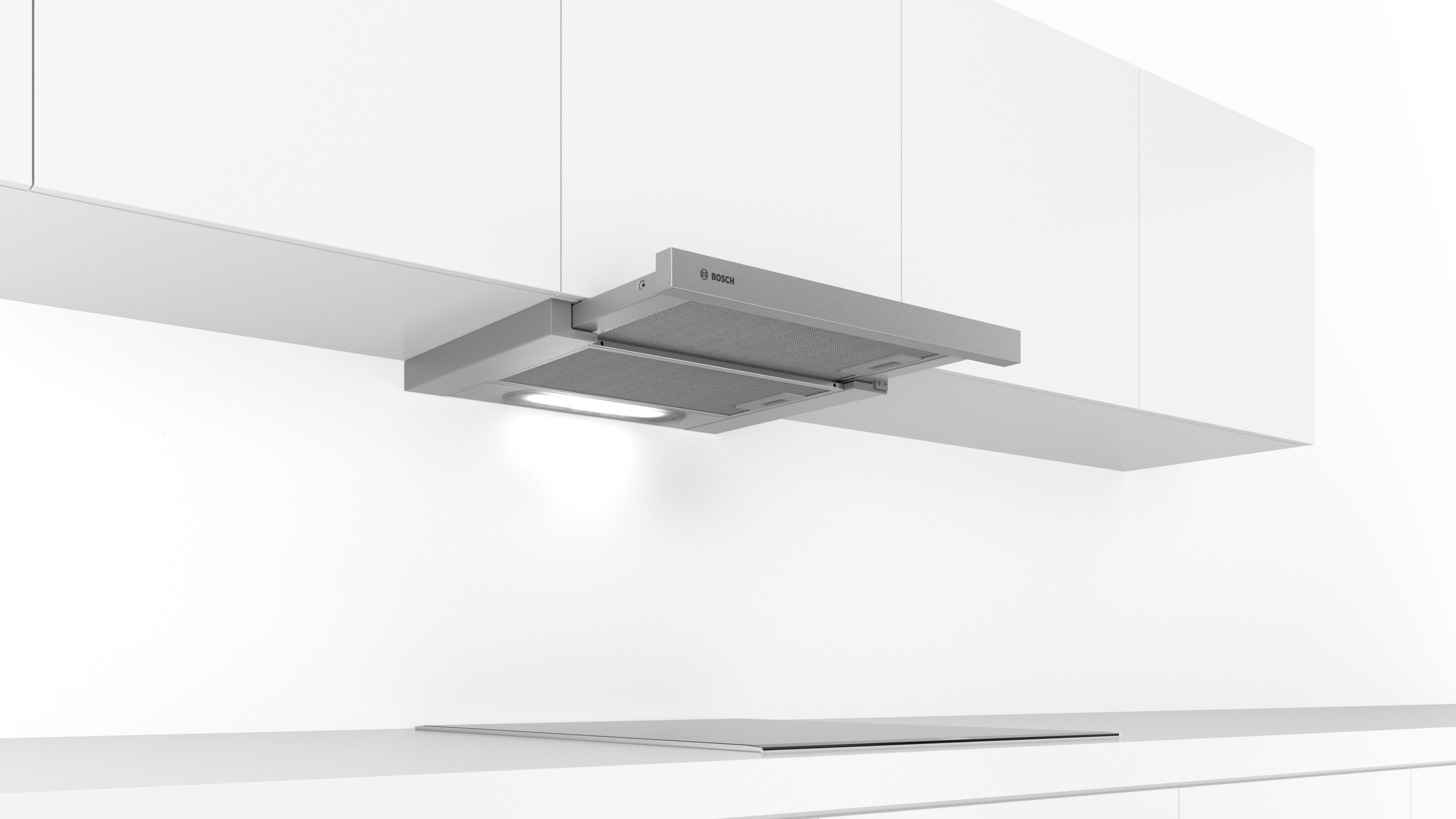 Una campana extractora plateada instalada sobre una placa de cocina, con luz y dos armarios arriba.