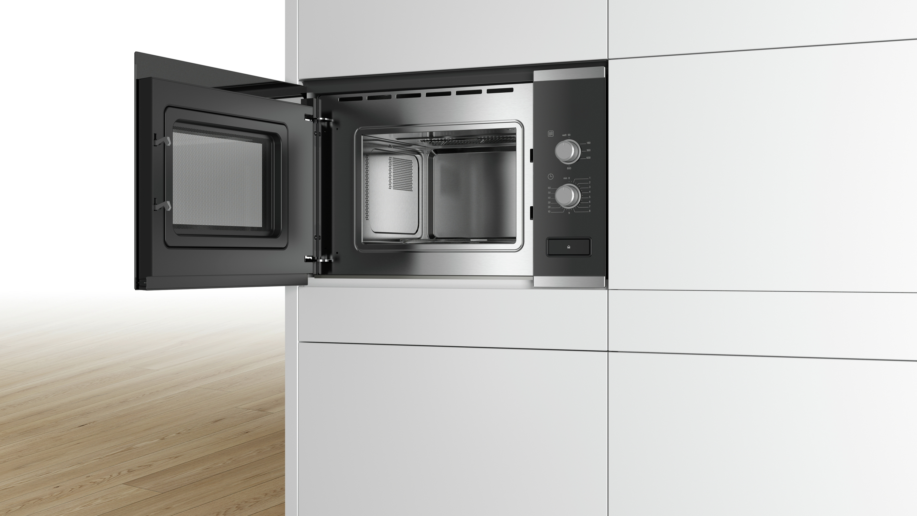 Microondas, puerta abierta. Interior acero inoxidable. Armarios blancos y suelo de madera clara.