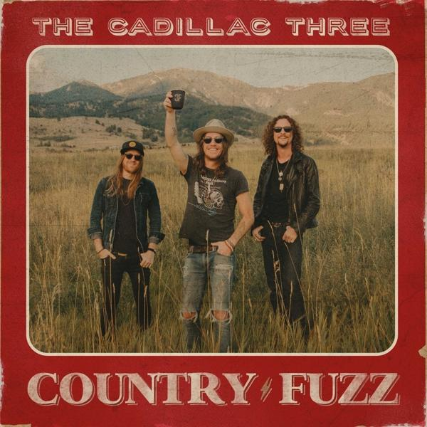 Album borítója három férfival egy mezőn, a The Cadillac Three zenekar. Piros háttér.
