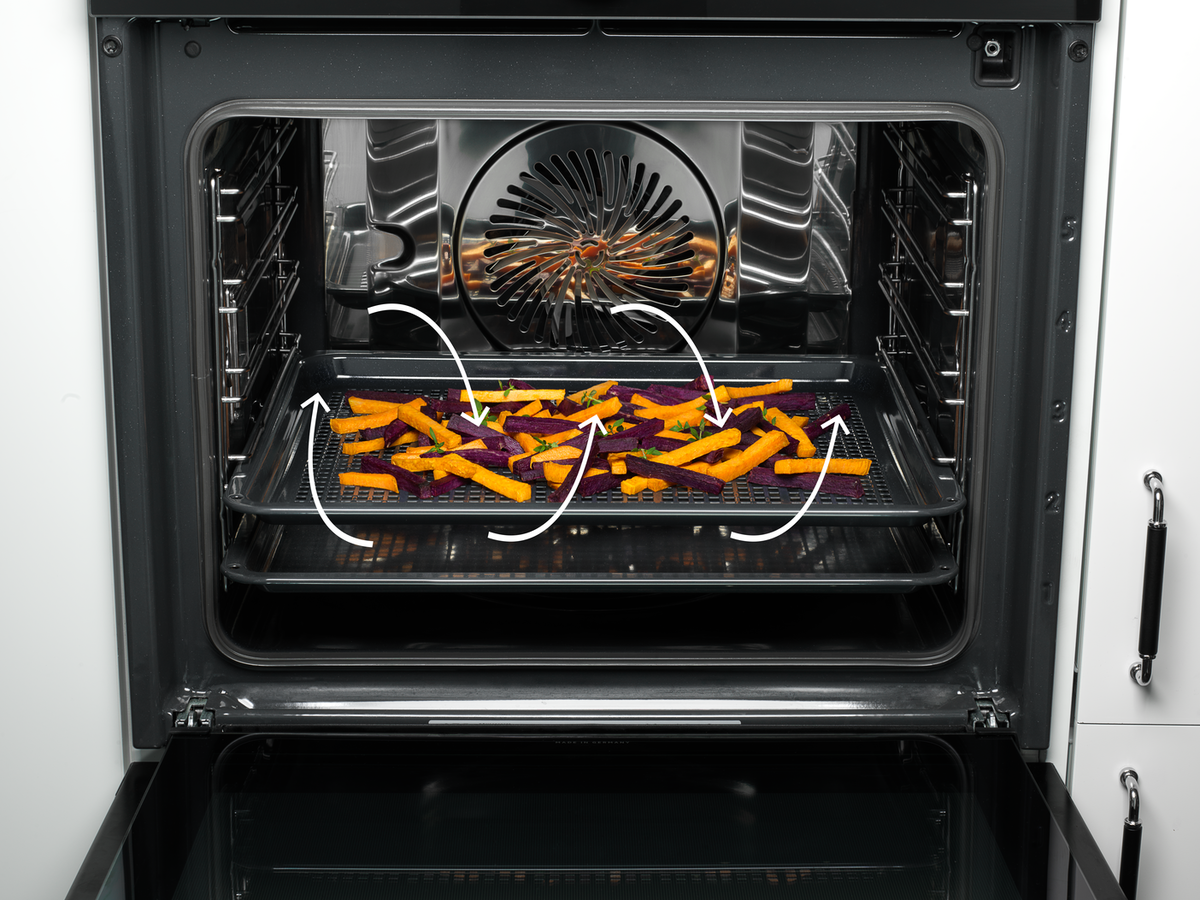 Intérieur du four avec plateau de frites oranges et violettes. Des flèches montrent la circulation de l'air.
