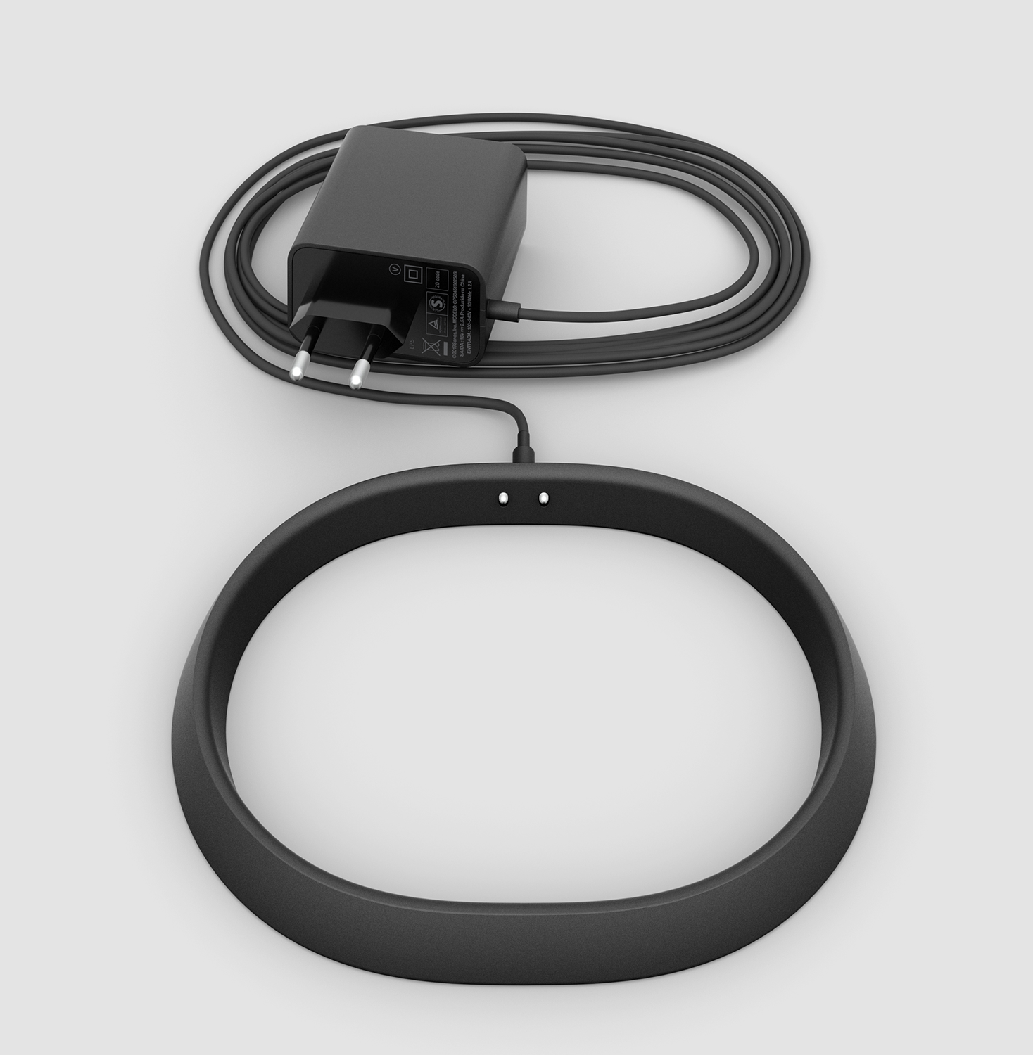 A black ring with charger and cable. The ring is connected to a power adapter.