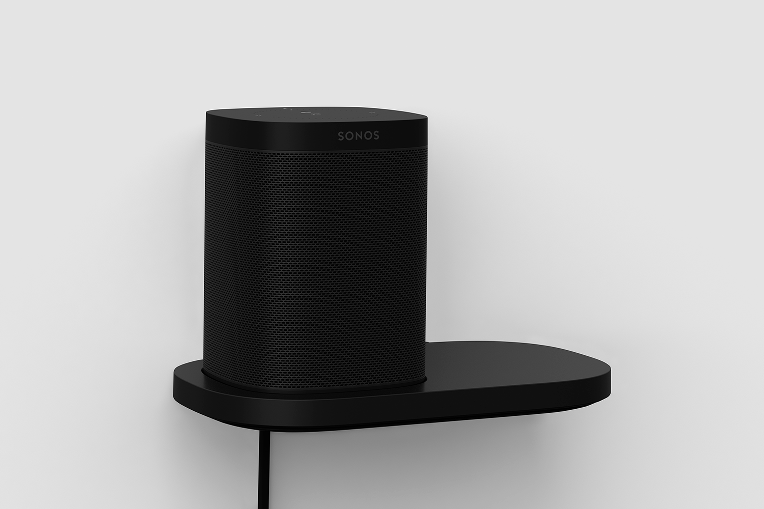 Black Sonos speaker on a black shelf attached to a white wall. The shelf has a rounded edge.