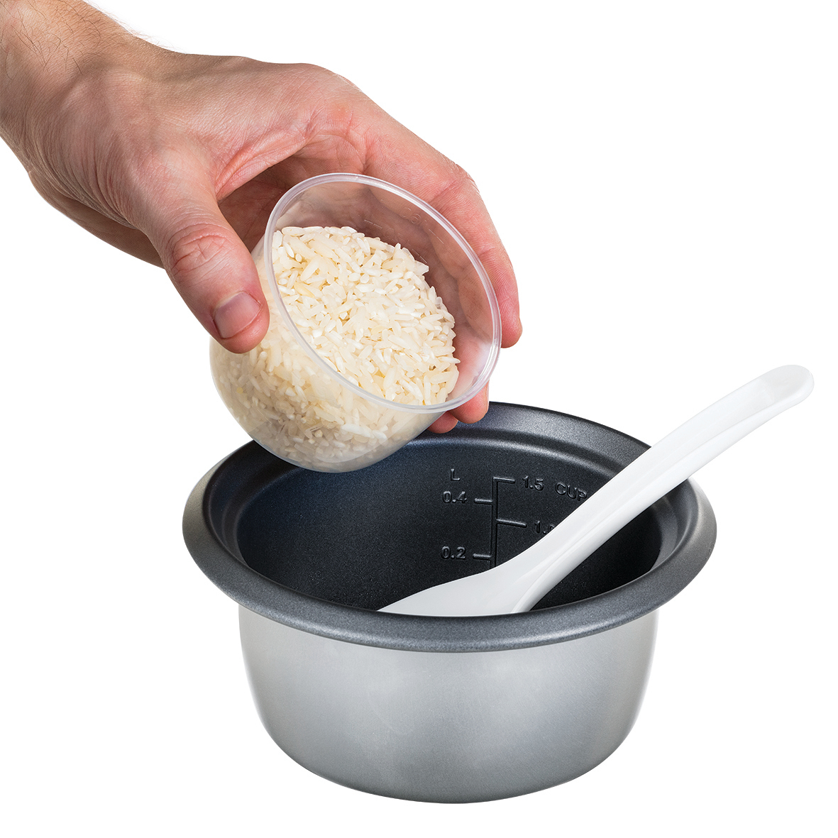 Eine Hand gießt Reis aus einem durchsichtigen Becher in einen Reiskocher mit einem weißen Löffel darin.