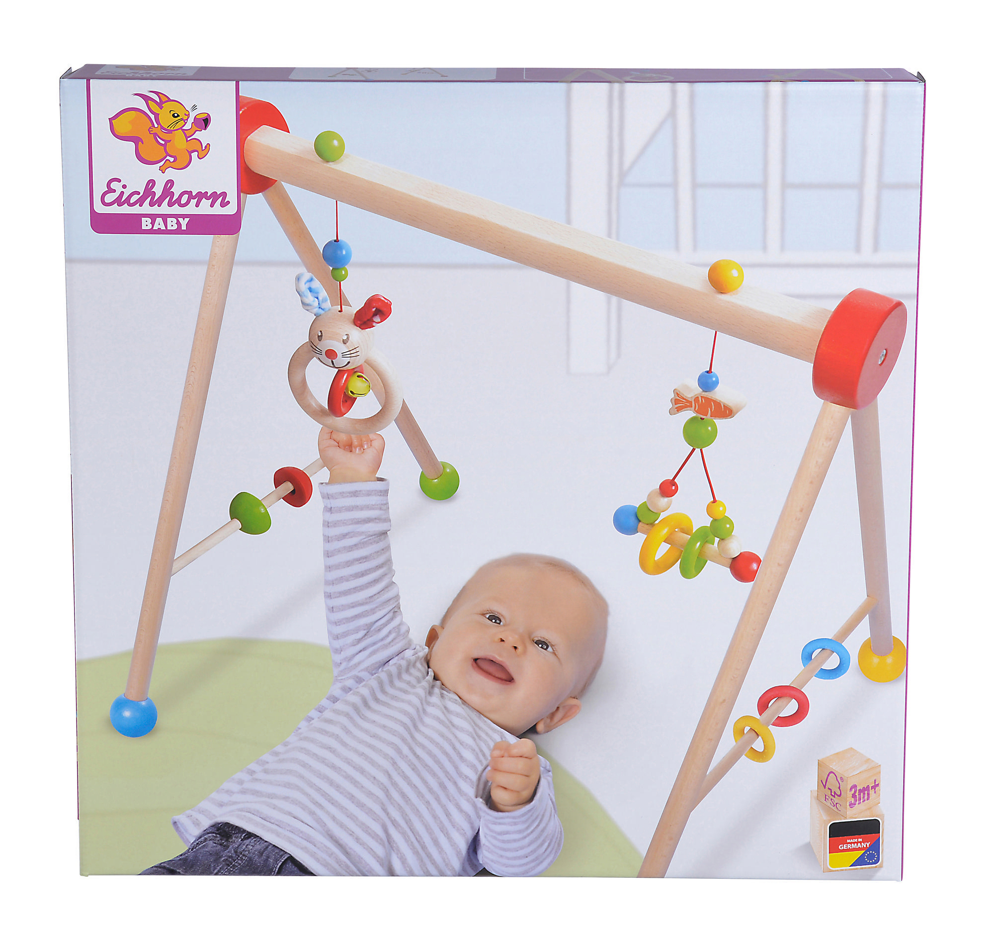 Baby spielt mit einem Holzspielgerät, liegt auf einer Matte, mit lächelndem Gesicht und Spielzeug.