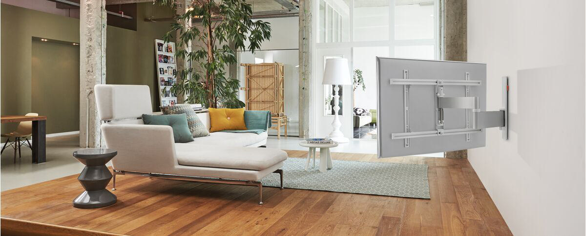 Ein Wohnzimmer mit Sofa, Beistelltisch und einem an der Wand montierten Fernseher.