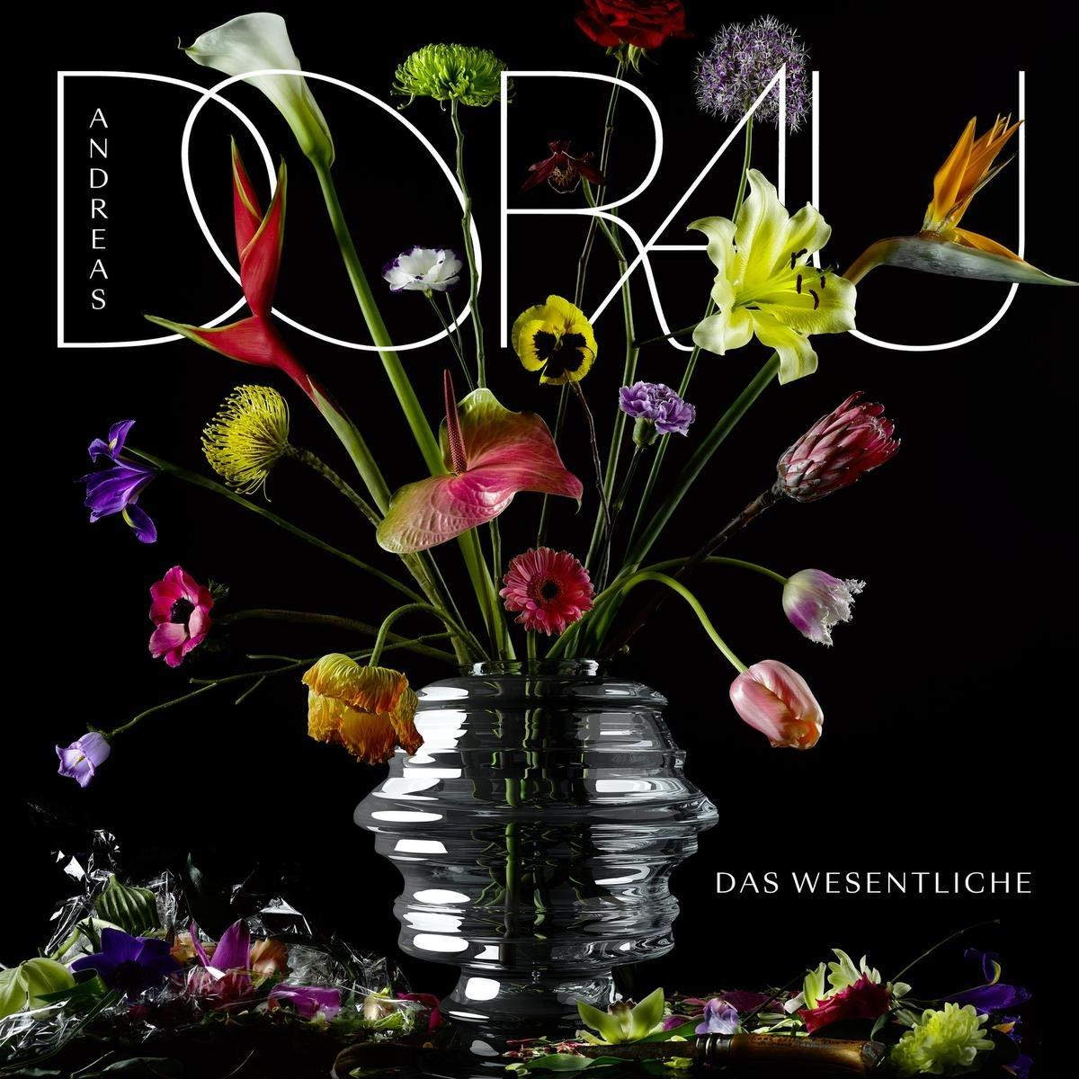 Eine Vase mit bunten Blumen, darunter Orchideen, Lilien und Tulpen, auf schwarzem Hintergrund.