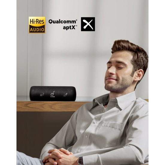 Siyah bir hoparlörle rahatlayan bir adam. Hoparlörde üç düğme var, Hi-Res Audio ve aptX logoları görünür.