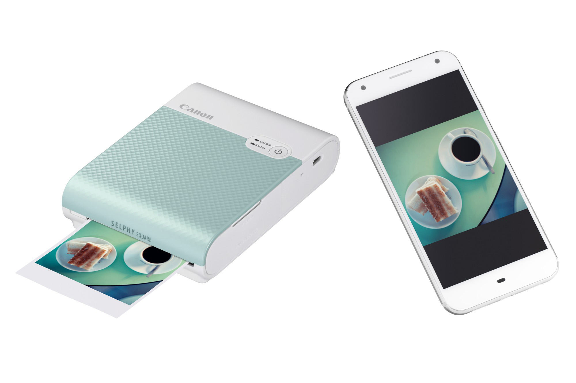 Ein Canon Selphy Square Drucker druckt ein Foto. Ein Telefon mit Foto auf einem Tisch.