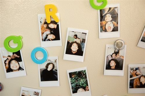 Fotos pegadas a un refrigerador con imanes. Se ven letras e imágenes de personas.