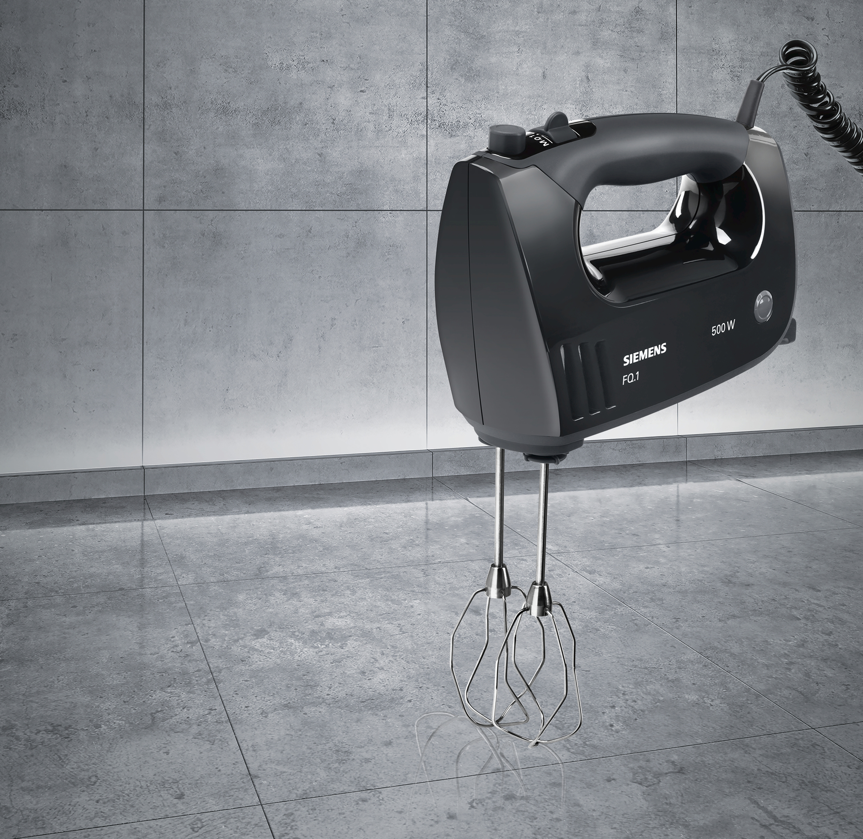 Schwarzer Handmixer auf grauem Untergrund. Silberne Schläger hängen unten.