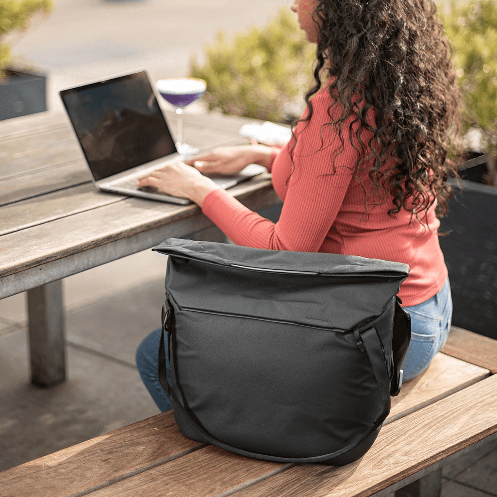 Una donna usa un laptop a un tavolo con una borsa nera.