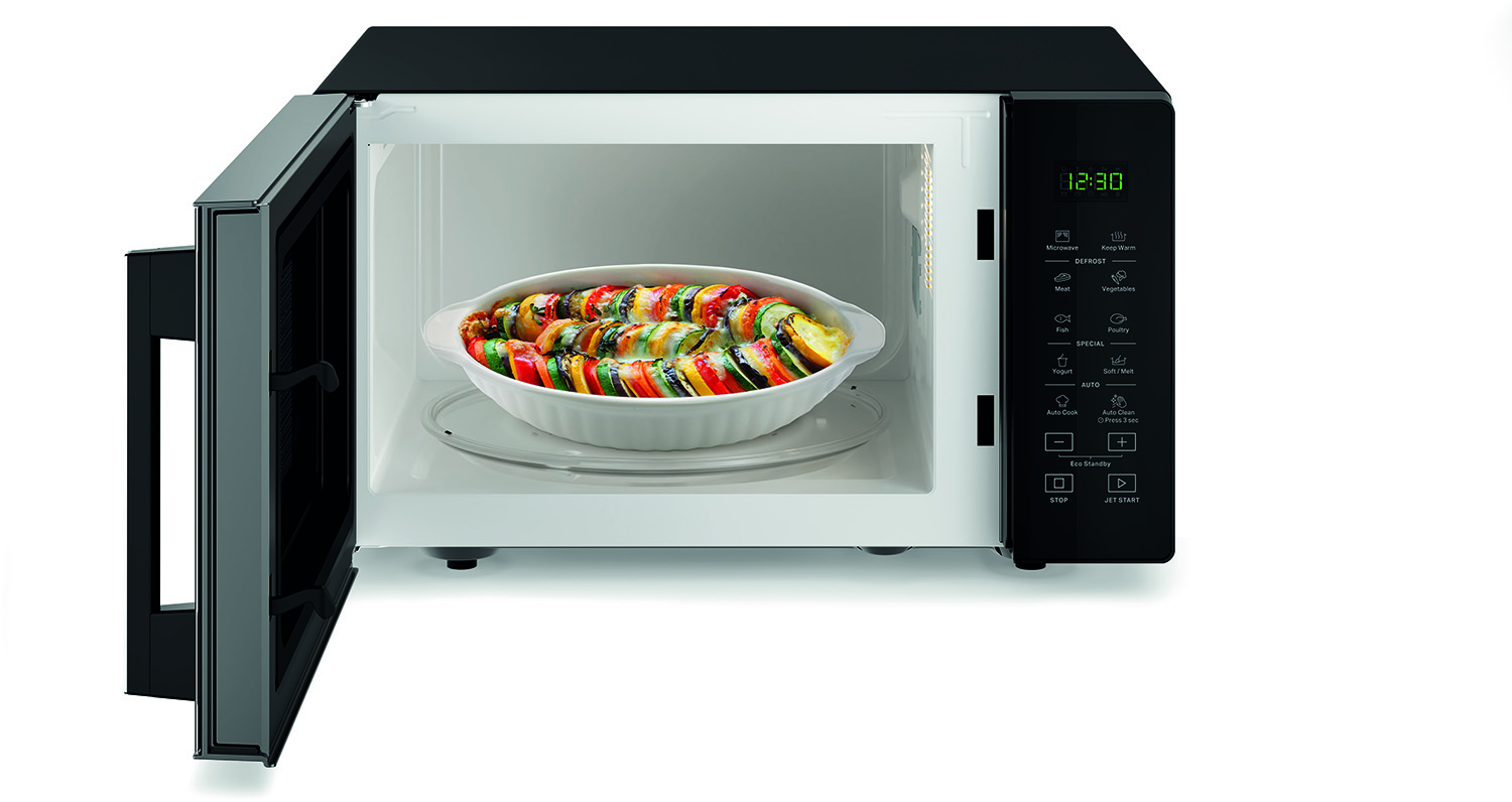 Magnetron met open deur, met een schaal met kleurrijk eten.