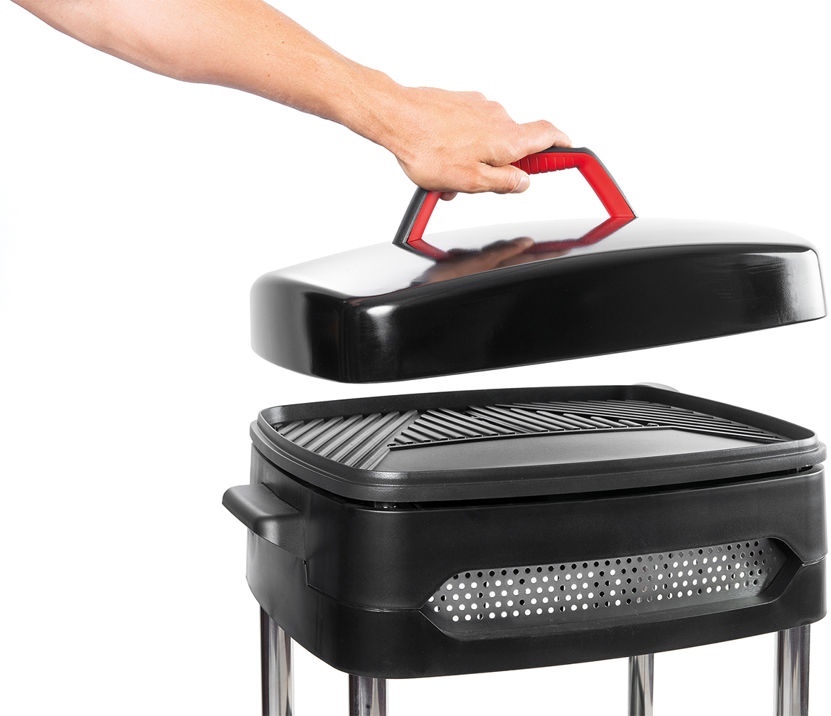 Een hand die een deksel van een zwarte grill tilt.