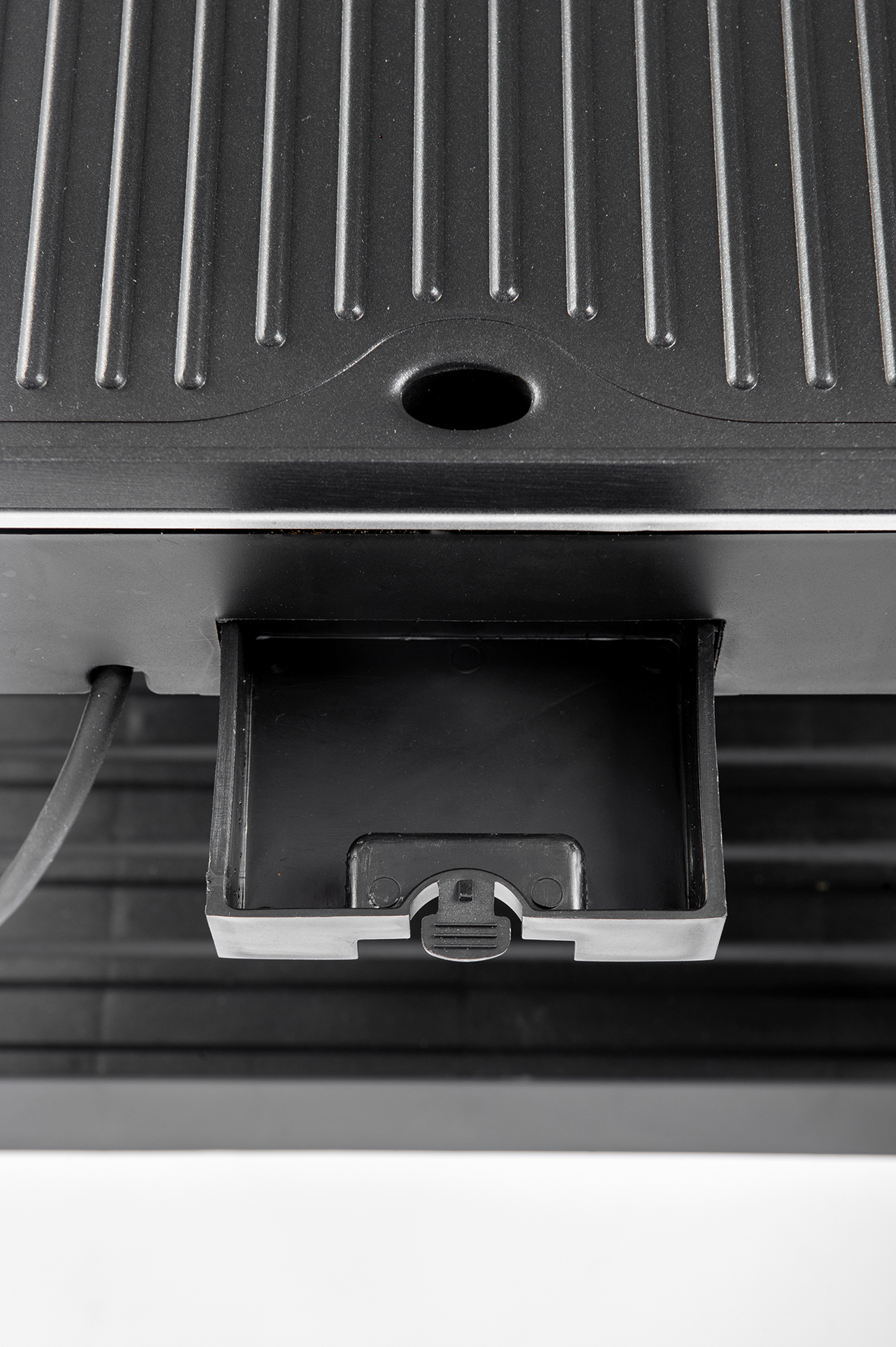 Close-up of a black appliance with a slotted top and a removable drawer at the bottom.