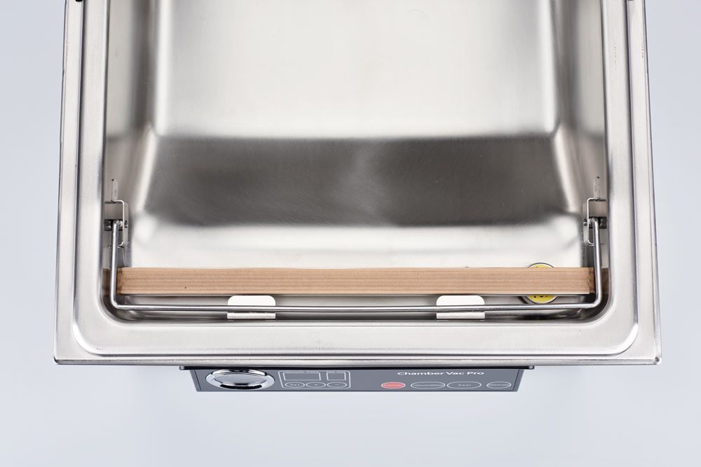 Een roestvrijstalen vacuümsealerkamer met een houten balk.