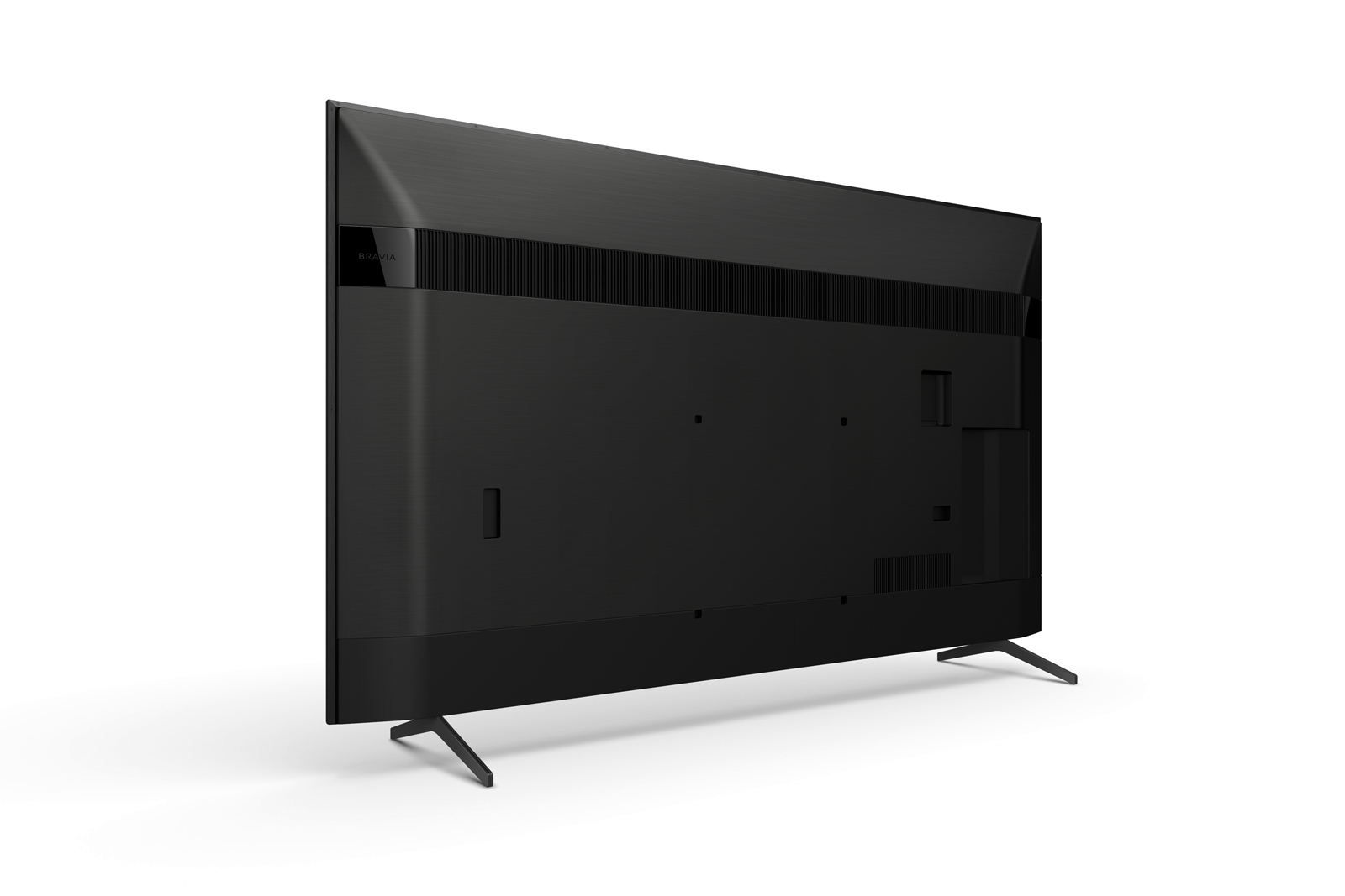 Parte trasera de TV Sony negra con ventilación, puertos y patas sobre fondo blanco.