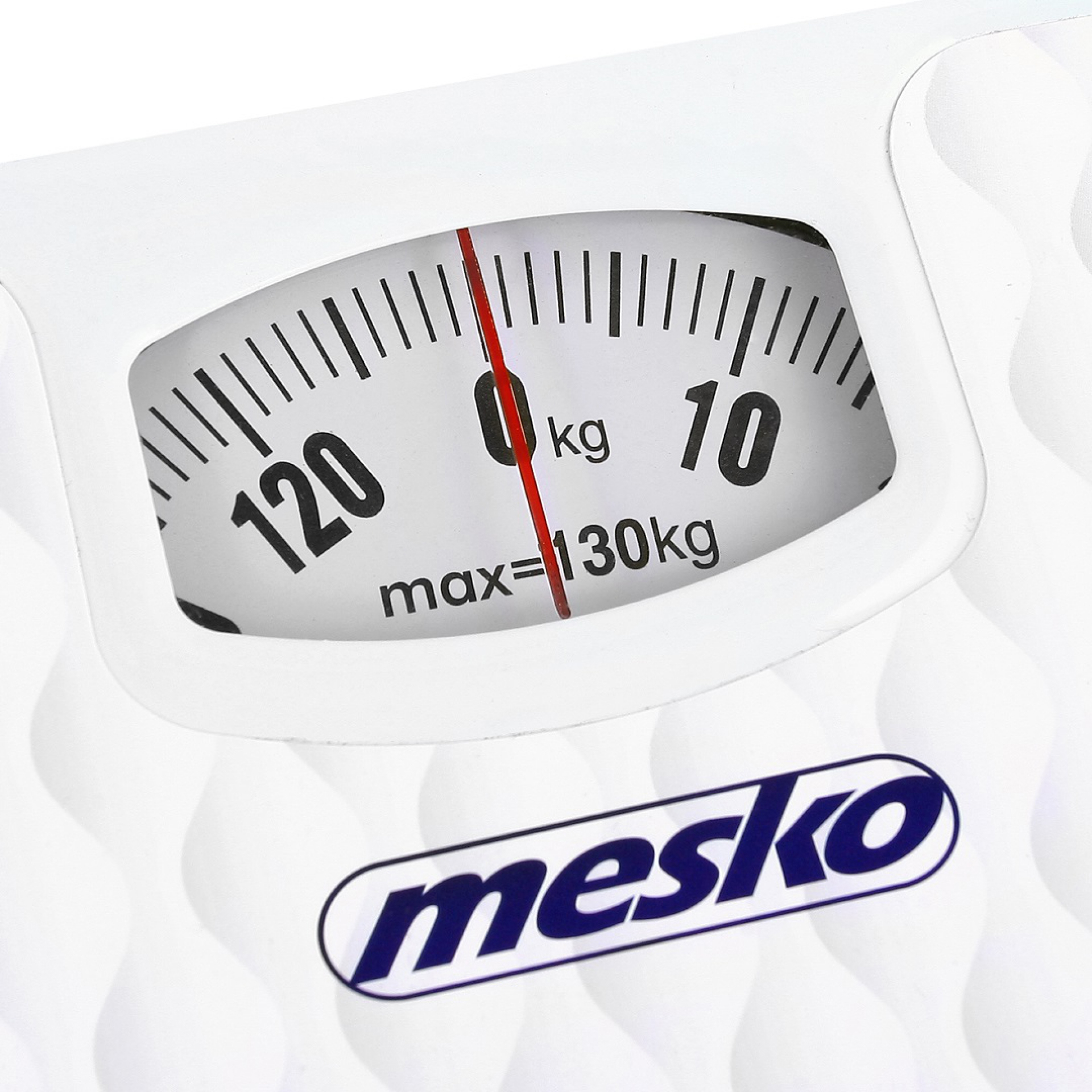 Közelkép egy fehér mérlegről, amely 0 kg-ot és egy piros tűt mutat.