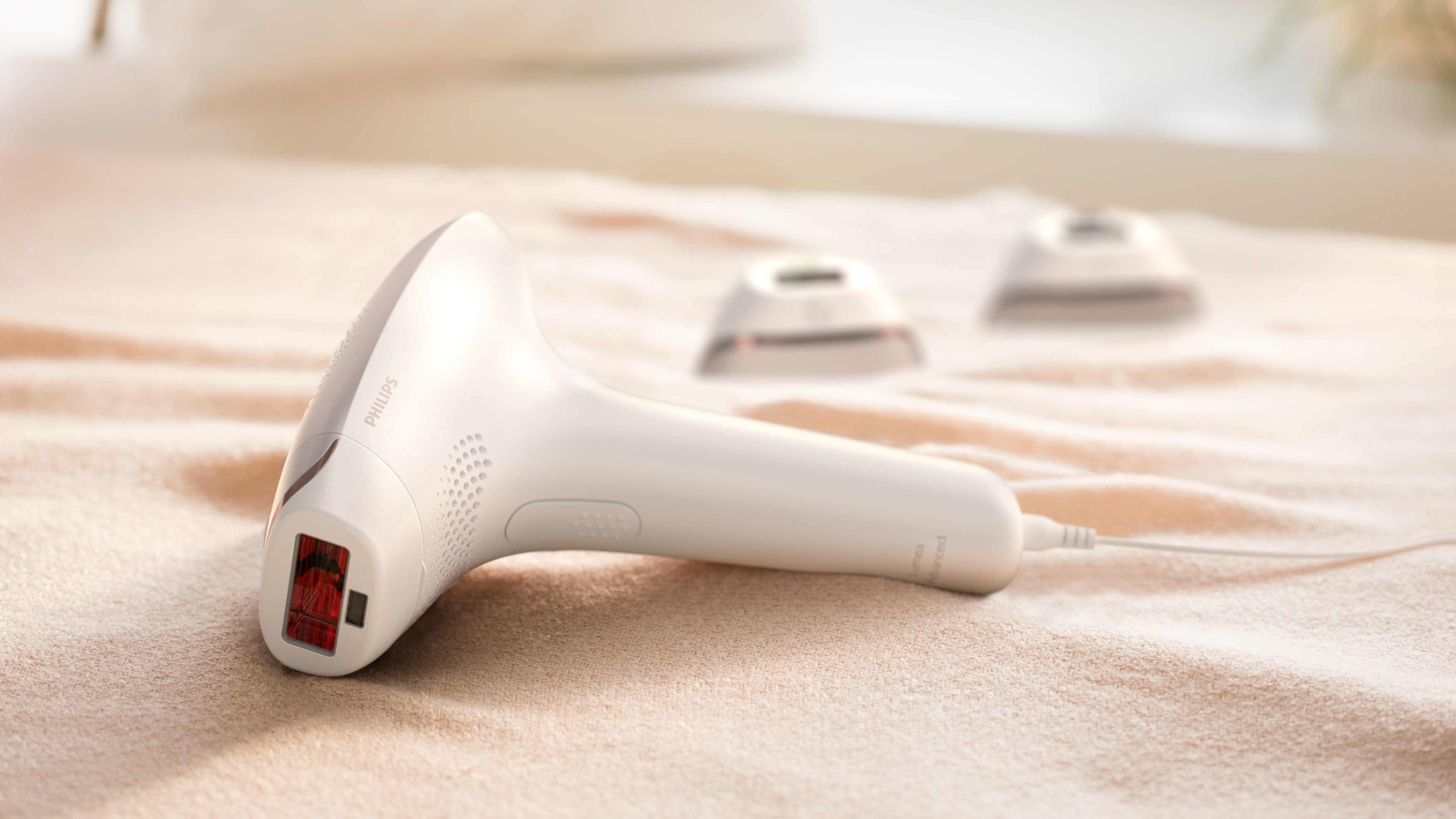 White Philips Lumea device with two attachments on a beige surface.