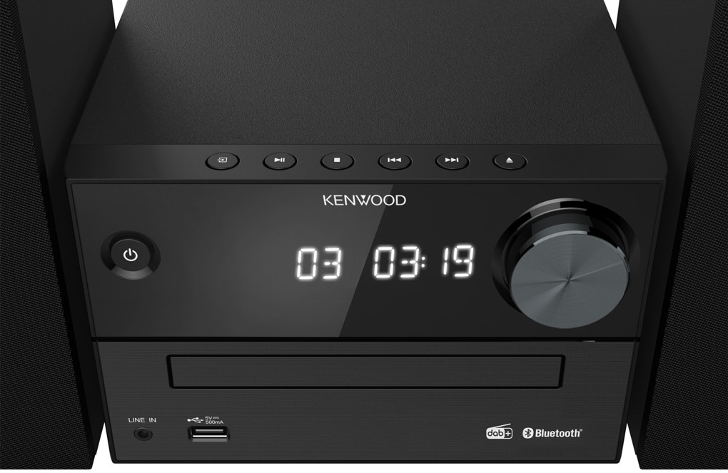Un mini-système hi-fi Kenwood est montré. Il est noir avec un affichage numérique et des boutons.