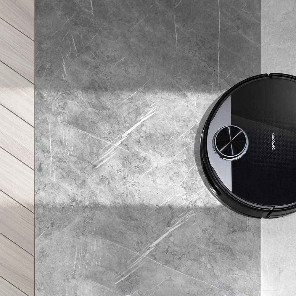 Aspiradora robot en un piso gris y de madera.