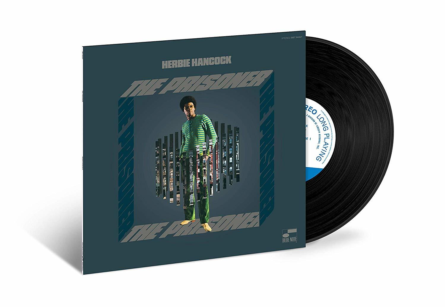 Herbie Hancock 'The Prisoner' albumjának borítója. Egy zöld inget viselő férfi egy városkép előtt áll. Jobbra egy fekete bakelit lemez látható.