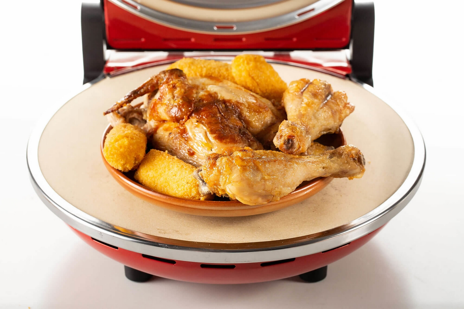 Un plato con pollo cocido y croquetas de patata se encuentra en un horno rojo.