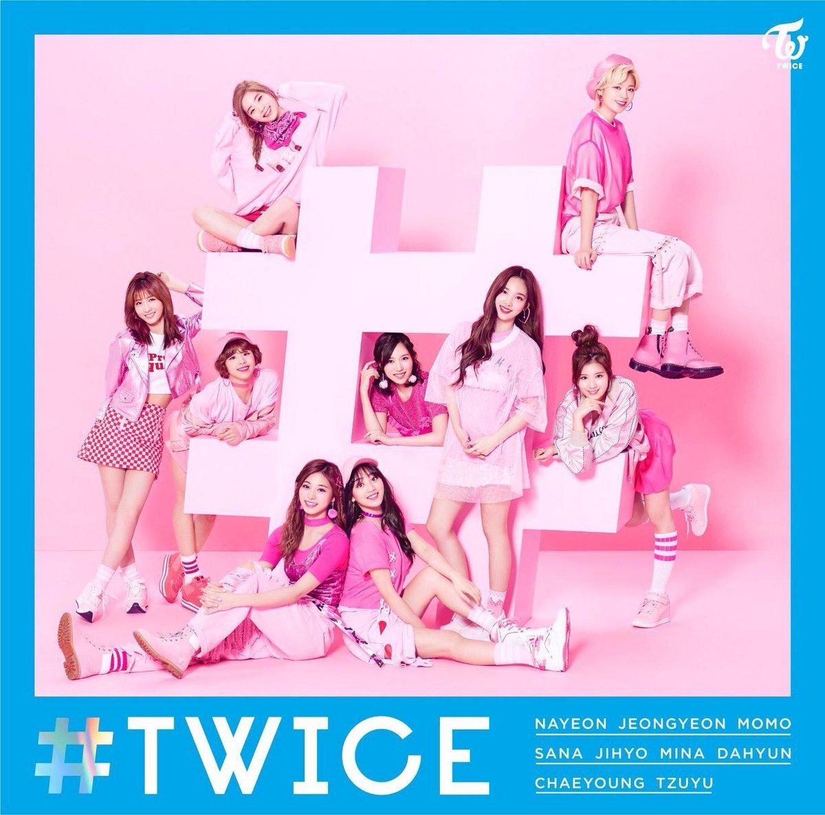 Twice csoportkép. Kilenc nő rózsaszín ruhában, egy nagy hashtag szimbólum körül pózol.