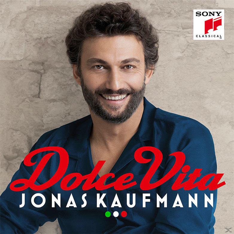Dolce Vita album borító. Jonas Kaufmann mosolyog, kék inget visel. Piros szöveg barna háttéren.