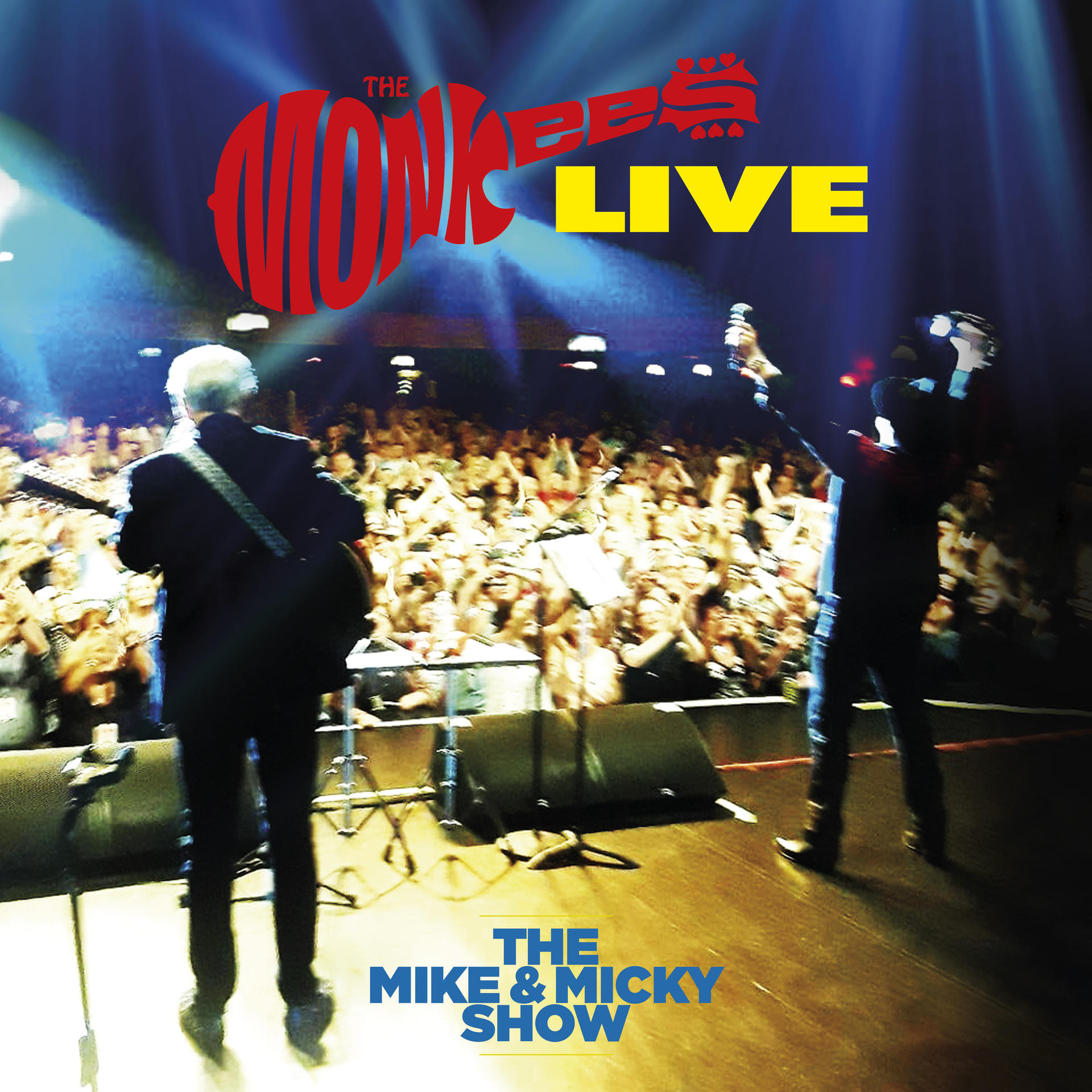 Scène de concert en direct avec les membres du groupe, la foule. Titre 'The Monkees Live' en haut, 'The Mike & Micky Show' en bas.