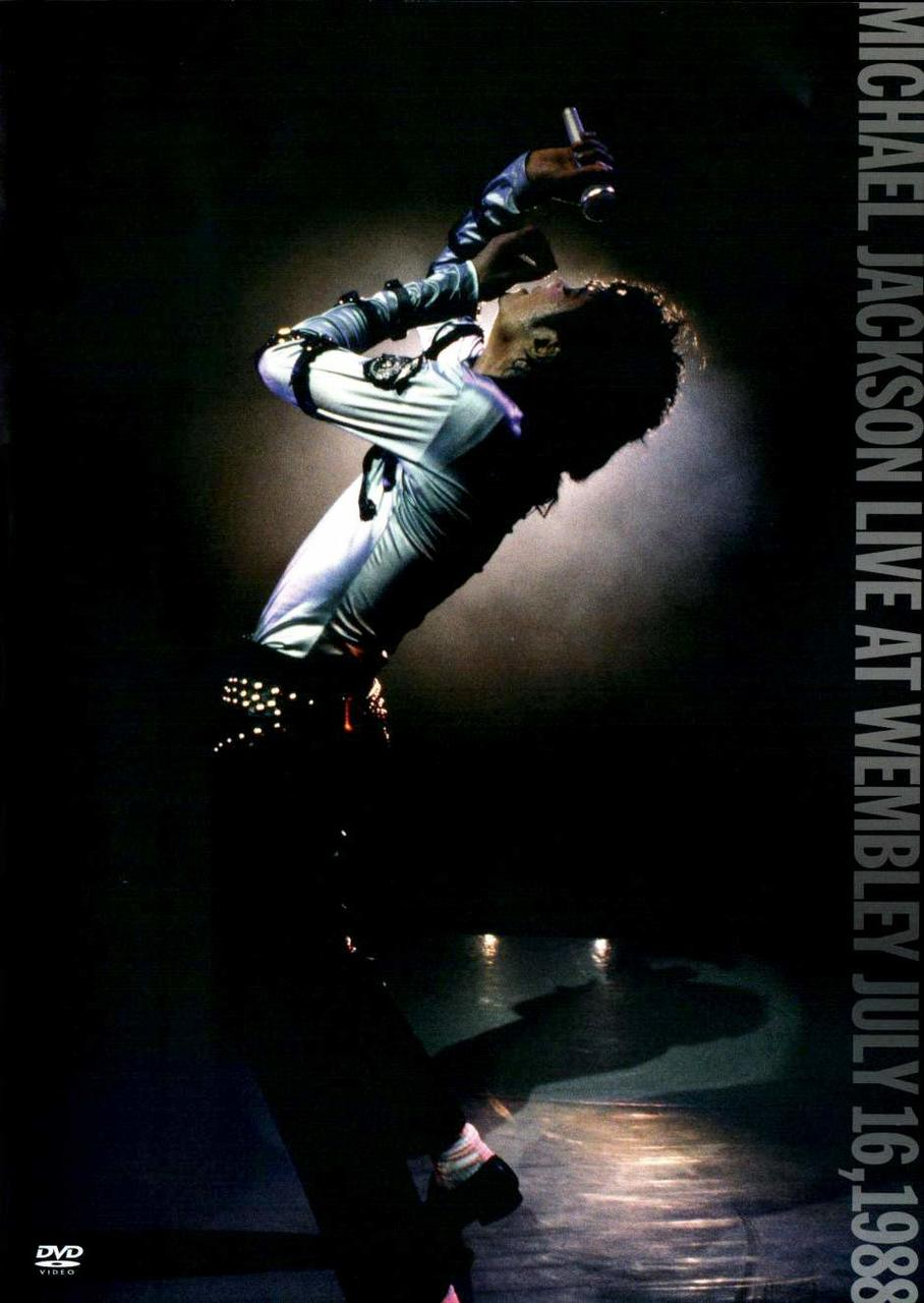 Michael Jackson auf der Bühne, singt in ein Mikrofon. Trägt ein silbernes Outfit. Silhouette im Dunkeln.