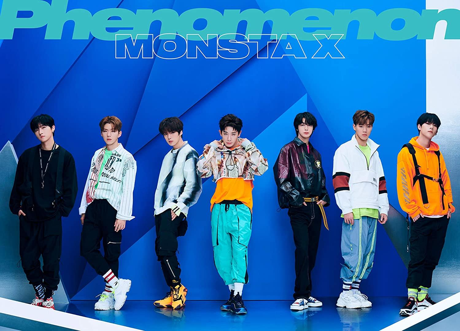 Group of seven men in colorful outfits stands against a blue backdrop.