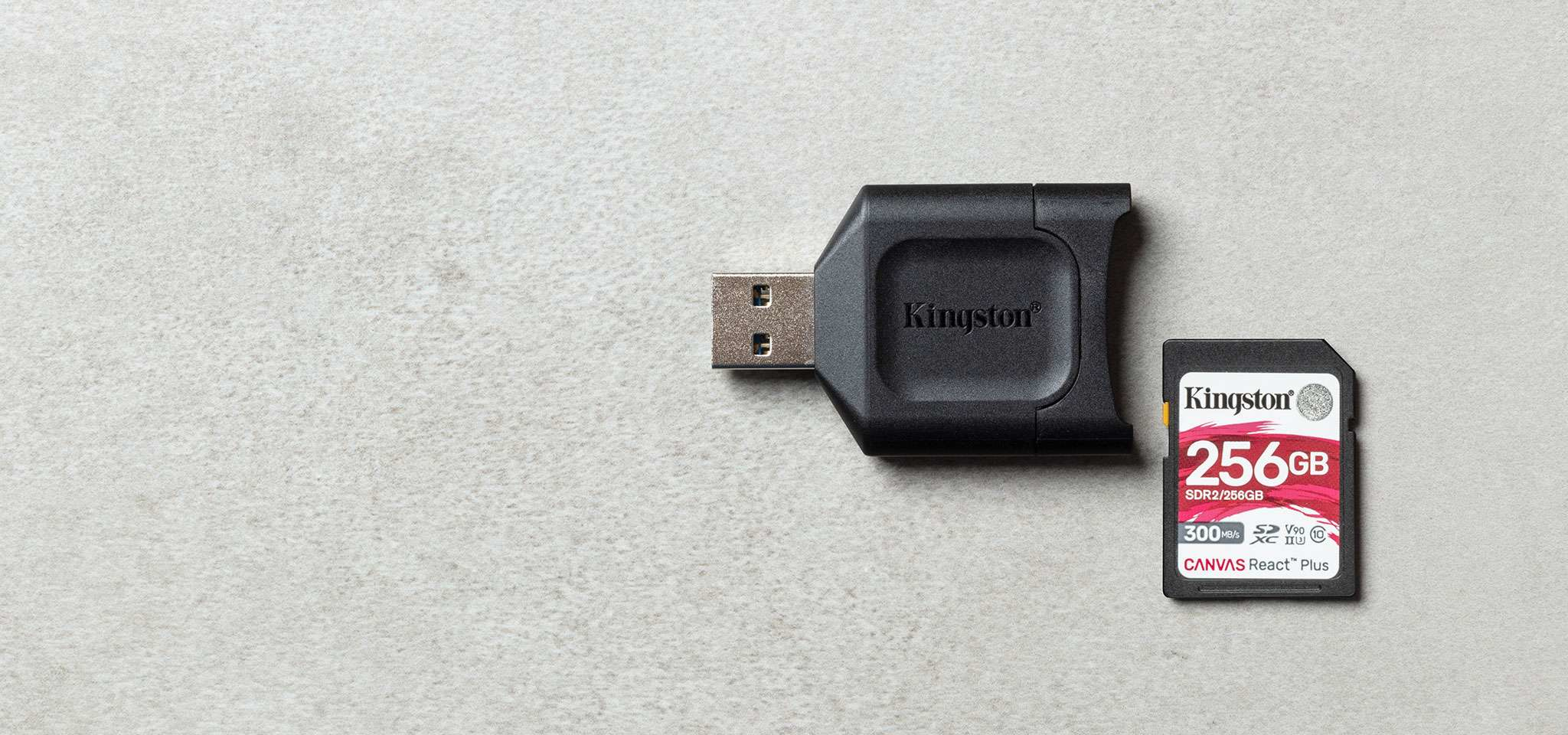 Ein Kingston USB-Kartenleser und eine 256 GB Kingston SD-Karte liegen auf einer grauen Oberfläche.