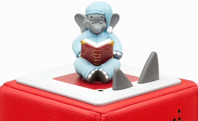 Eine rote Box mit weißer Oberseite hat eine Figur oben drauf, mit zwei Haifischflossen. Die Figur liest.