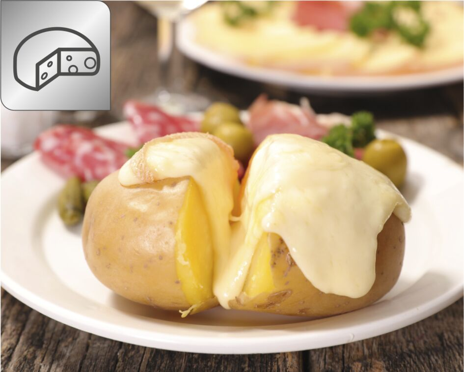 Une pomme de terre au four avec du fromage et d'autres garnitures sur une assiette blanche.