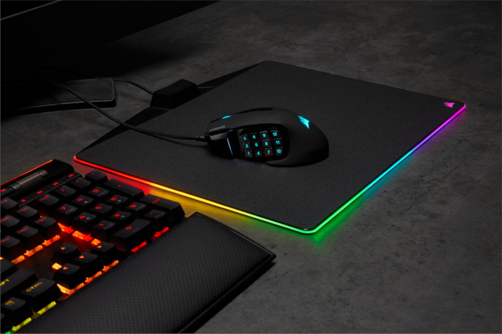 Gaming mouse on a mousepad with illuminated edges and keyboard.