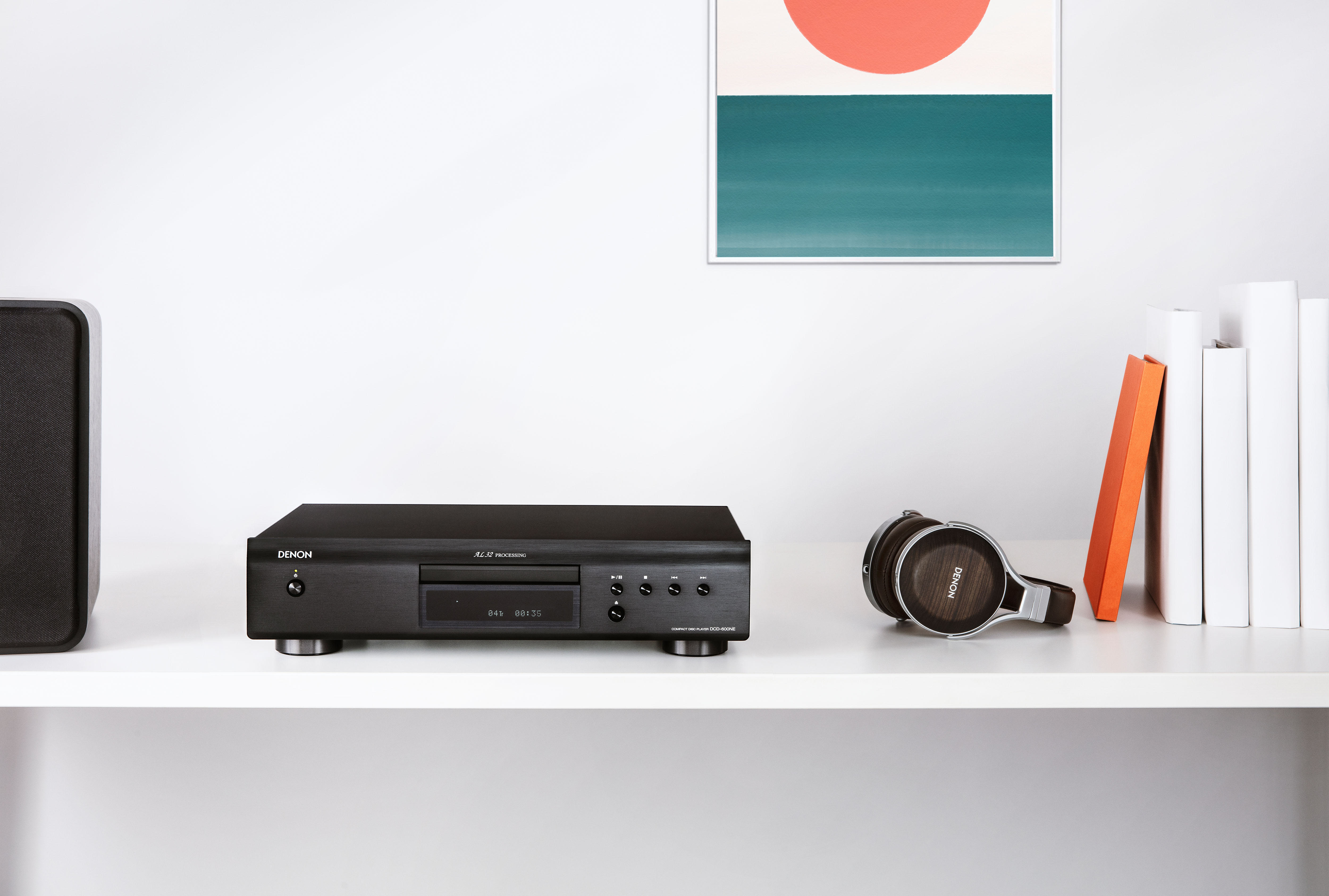 Schwarzer Denon CD-Player, Kopfhörer und Bücher auf weißem Regal.