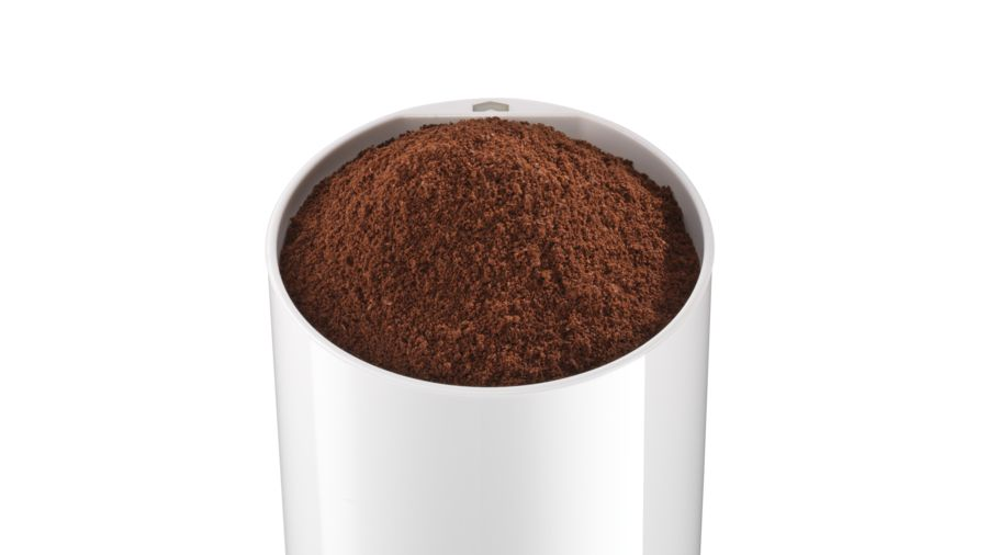 Un recipiente blanco lleno de posos de café marrón oscuro.