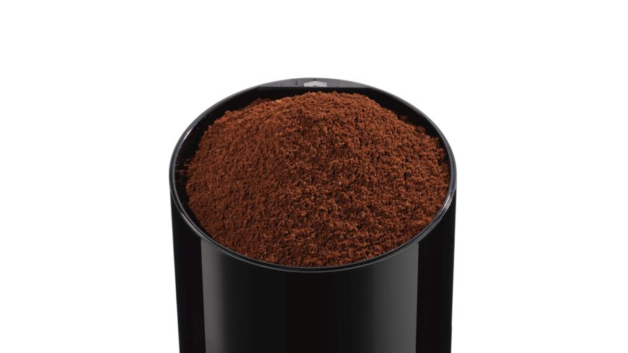 Primer plano de molinillo de café lleno de café molido. Marrón oscuro, contenedor negro.